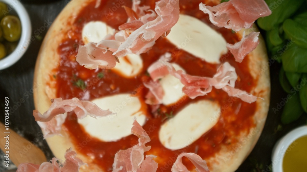 Super slow motion of falling fresh basil leaves on pizza dough with sugo, top down view Super slow motion of falling fresh basil leaves on pizza dough with sugo, top down view
