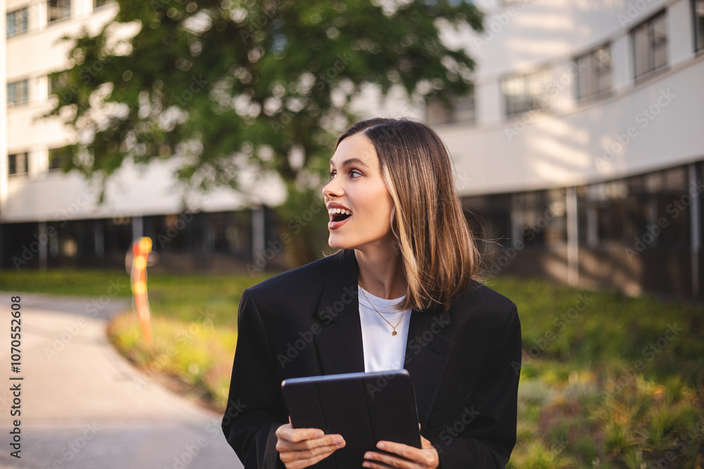 Beauty short hair woman holding tablet. Beautiful smiling fashionable business woman standing in front of business center have conversation, look at side, look happy. Amazed woman meet delegation Beauty short hair woman holding tablet. Beautiful smiling fashionable business woman standing in front of business center have conversation, look at side, look happy. Amazed woman meet delegation