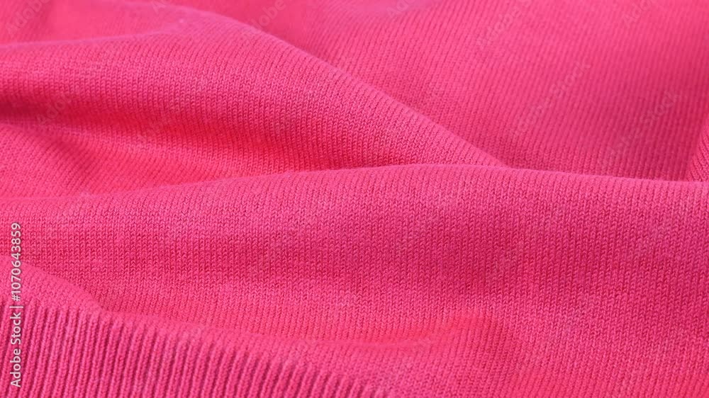 Pink color cotton jersey taffy shade. The textile background laid in folds rotates on the display case. Background on the theme of fashion, design, natural fabrics. Pink color cotton jersey taffy shade. The textile background laid in folds rotates on the display case. Background on the theme of fashion, design, natural fabrics.