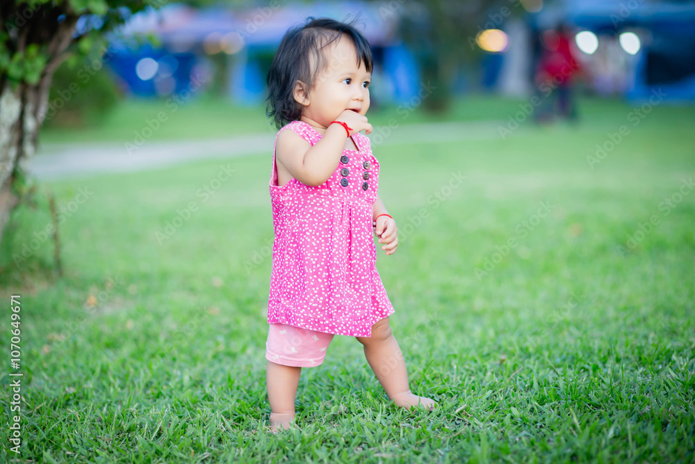 Baby girl walking outdoors dressed in pink stripped dress. Happy kid. Happy childhood. Baby girl walking outdoors dressed in pink stripped dress. Happy kid. Happy childhood.