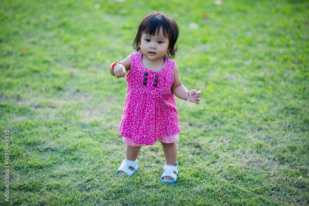 Baby girl walking outdoors dressed in pink stripped dress. Happy kid. Happy childhood. Baby girl walking outdoors dressed in pink stripped dress. Happy kid. Happy childhood.
