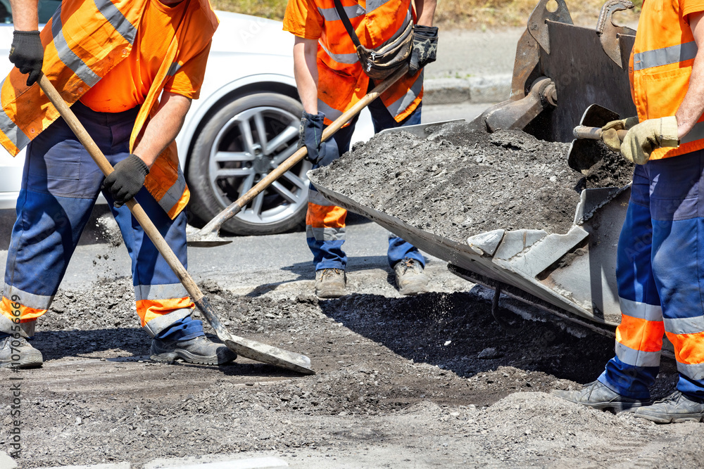 Workers repairing a road with asphalt under the midday sun in an urban setting Workers repairing a road with asphalt under the midday sun in an urban setting