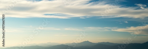 A view of the mountains in the distance with a clear blue sky and white clouds