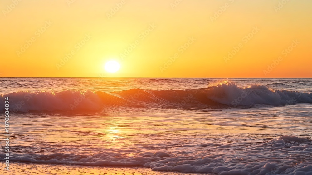 Obraz premium Golden sunset over ocean waves creating a serene atmosphere with vibrant colors and gentle reflections on the water