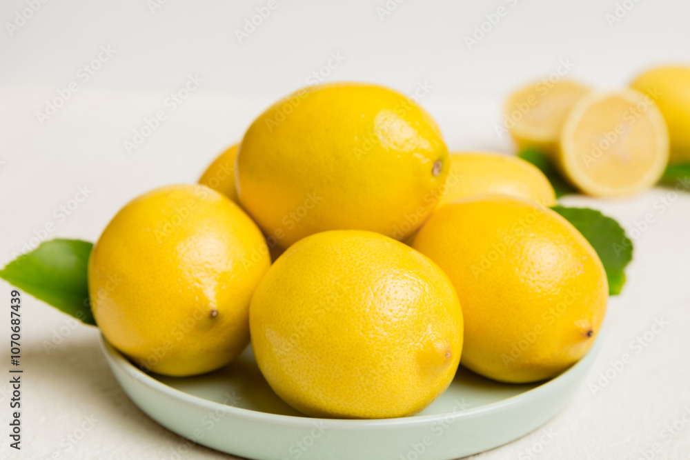 Fresh cutted lemon and whole lemons over round plate on colored background. Food and drink ingredients preparing. healthy eating theme top view vith copy space Fresh cutted lemon and whole lemons over round plate on colored background. Food and drink ingredients preparing. healthy eating theme top view vith copy space