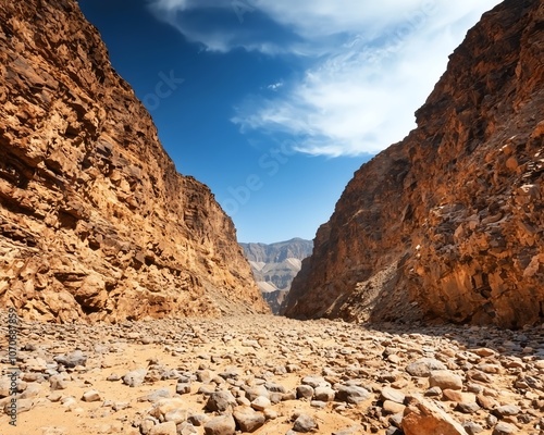 Rocky canyon landscape with blue sky and clouds.