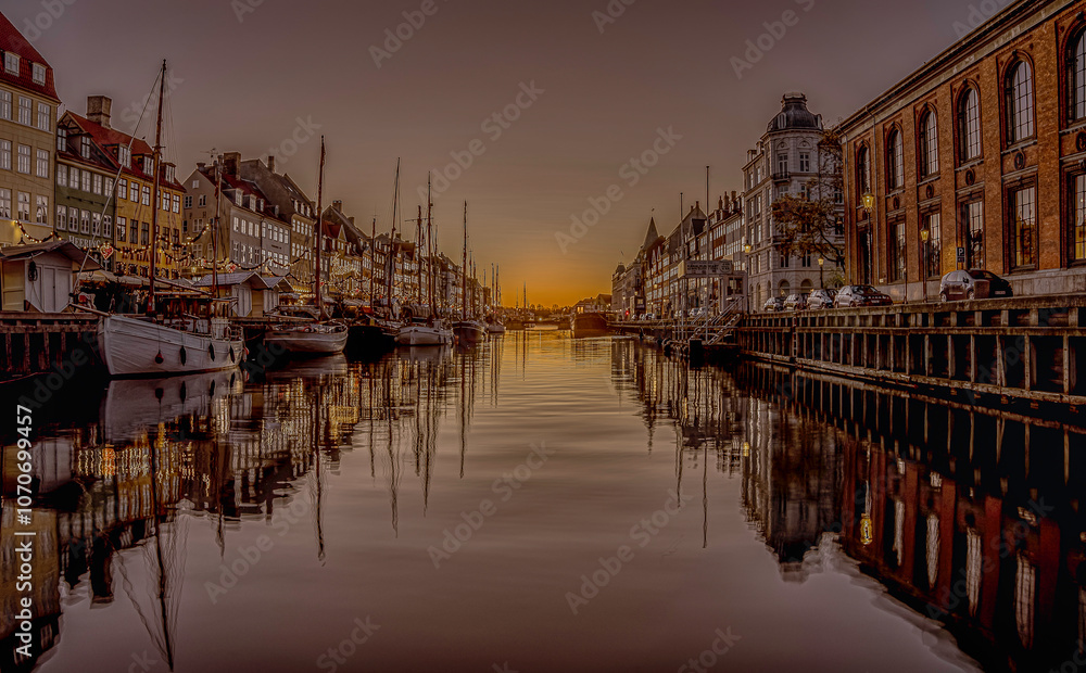 Nyhavn Canal in Copenhagen as the sun rises and reflects on the calm water