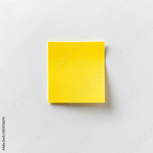 Yellow sticky note on white surface with soft shadow