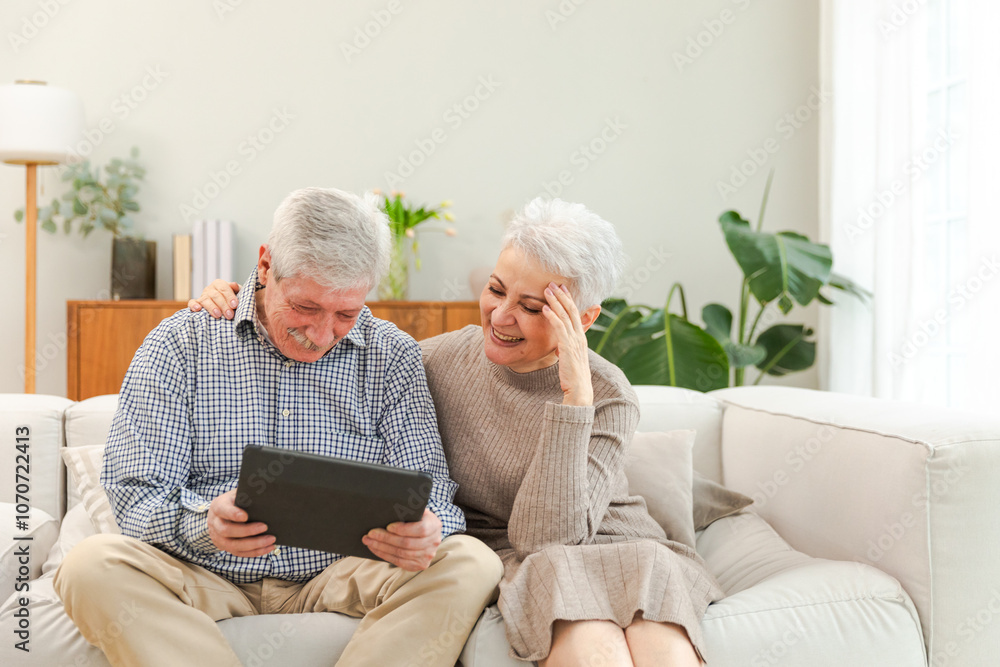 Senior old couple with tablet watching video online. Husband wife spending time together at home. Happy modern mature senior couple using tablet for family entertainment. Old people modern technology Senior old couple with tablet watching video online. Husband wife spending time together at home. Happy modern mature senior couple using tablet for family entertainment. Old people modern technology