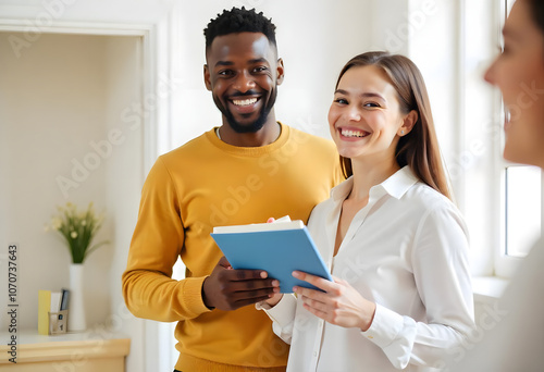 Group of three work colleagues in business casual cloths smiling and holding papers and notebooks in bright office space photo