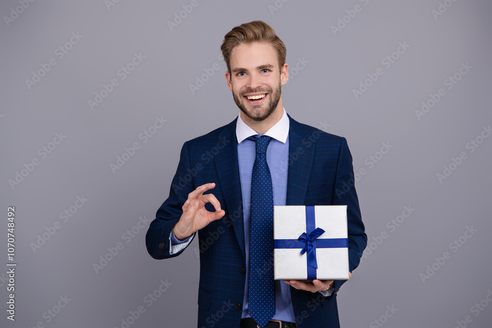 Business reward. Business man with corporate gift box isolated on grey. Corporate present. Mens day. Successful boss share gift box. Businessman prepare for romance date. Ok Business reward. Business man with corporate gift box isolated on grey. Corporate present. Mens day. Successful boss share gift box. Businessman prepare for romance date. Ok