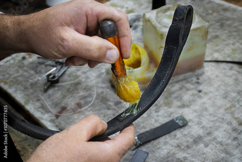 A saddler craftsman restores and creates animal harnesses and tack with leather. He cuts, glues, sews, paints. photo