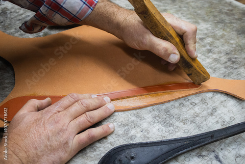 A saddler craftsman restores and creates animal harnesses and tack with leather. He cuts, glues, sews, paints.