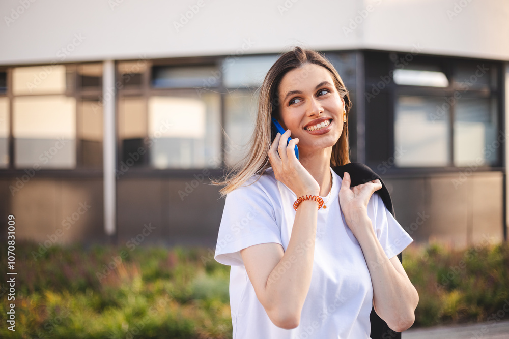 Beauty short hair woman holding jacket over shoulder. Professional businesswoman happily answering a phone call near office. Happy caucasian female using a mobile phone to communicate with partners. Beauty short hair woman holding jacket over shoulder. Professional businesswoman happily answering a phone call near office. Happy caucasian female using a mobile phone to communicate with partners.