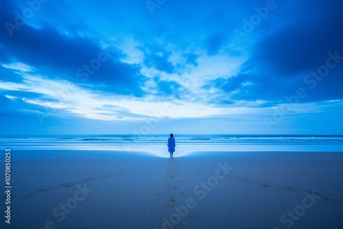 Silhouette of a person contemplating on the beach with deep blue waves and clouds