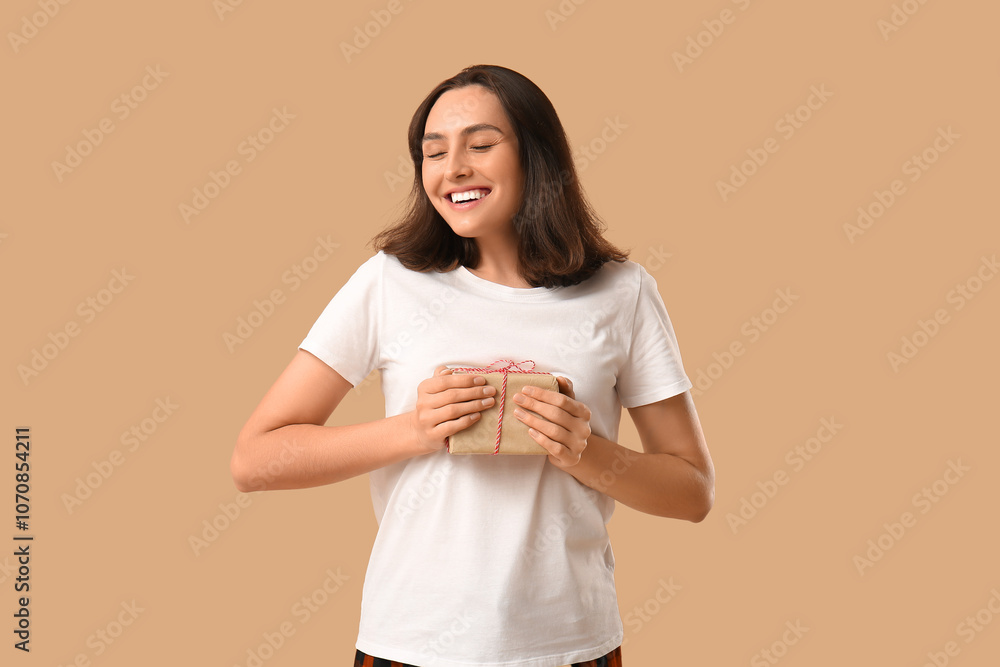 Beautiful young woman in pajamas with gift box on brown background Beautiful young woman in pajamas with gift box on brown background