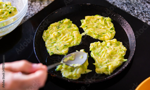 Cooking delicious zucchini pancakes in a frying pan photo