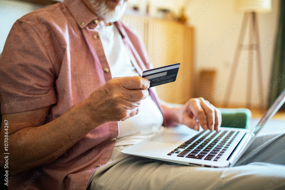 Senior man online shopping with laptop on couch at home Senior man online shopping with laptop on couch at home