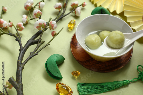 Bowl of tangyuan, Chinese decor and sakura on green background. Dongzhi Festival photo