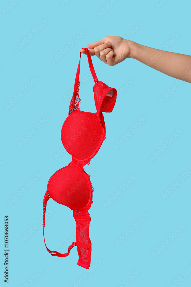 Female hand with sexy red bra on color background, closeup Female hand with sexy red bra on color background, closeup