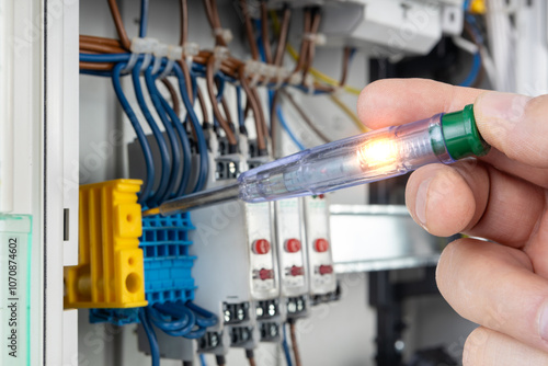 Hand Holding Voltage Tester in Electrical Panel