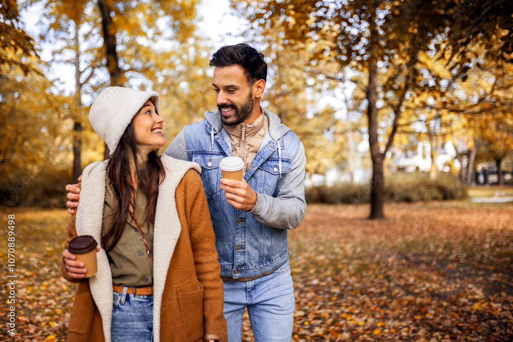 Pretty young couple drinking coffee in the park. Colorful autumn vibes in the park. Hugging, walking and holding hands. Pretty young couple drinking coffee in the park. Colorful autumn vibes in the park. Hugging, walking and holding hands.
