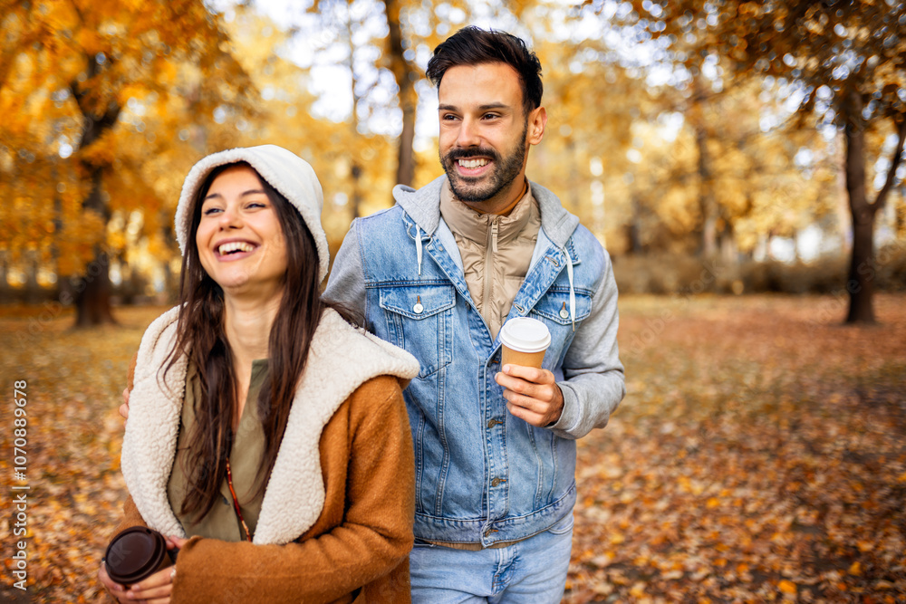 Pretty young couple drinking coffee in the park. Colorful autumn vibes in the park. Hugging, walking and holding hands. Pretty young couple drinking coffee in the park. Colorful autumn vibes in the park. Hugging, walking and holding hands.
