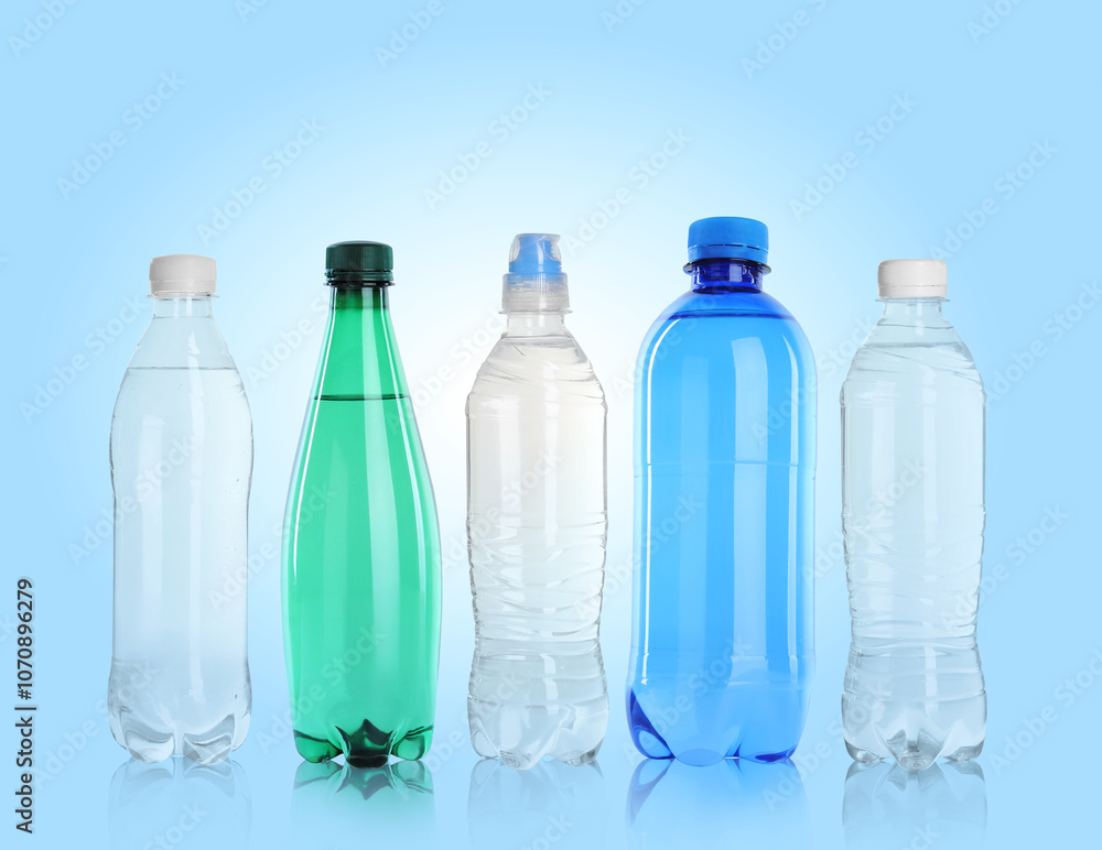 Different plastic bottles with water on light blue background Different plastic bottles with water on light blue background