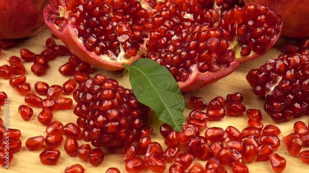 Whole and peeled pomegranates lie on a wooden board, close-up Whole and peeled pomegranates lie on a wooden board, close-up