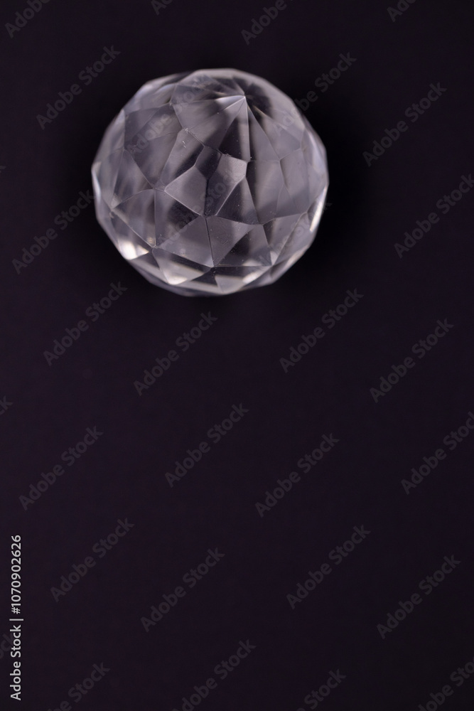 Faceted sphere, sparkling crystal on dark, black background. Large glass with light refraction, stone backdrop. Empty space for inscriptions Faceted sphere, sparkling crystal on dark, black background. Large glass with light refraction, stone backdrop. Empty space for inscriptions