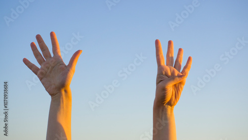 Woman hands showing or doing number nine gesture on blue summer sky background. Counting down, nine fingers up concept idea. photo