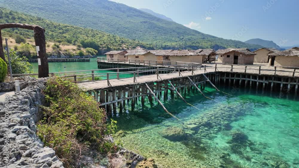 Wooden footbridge leading to reconstructed pile dwellings of Bay of bones archeological museum complex on lake Ohrid coast in north Macedonia Wooden footbridge leading to reconstructed pile dwellings of Bay of bones archeological museum complex on lake Ohrid coast in north Macedonia