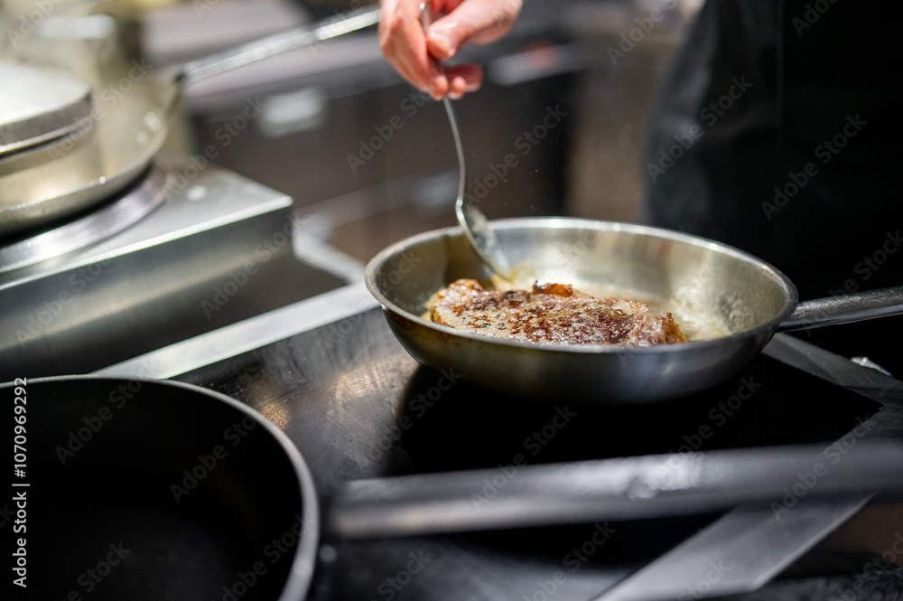 A close-up of hands cooking meat in a sizzling pan. The meat sears as bubbles form, set against a modern kitchen backdrop. A close-up of hands cooking meat in a sizzling pan. The meat sears as bubbles form, set against a modern kitchen backdrop.