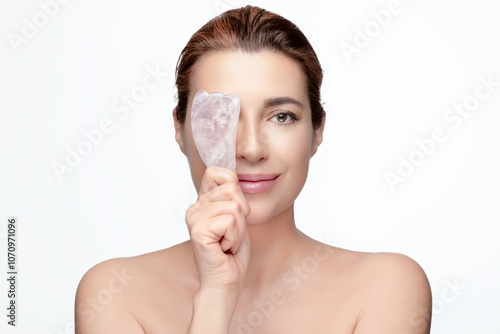 Woman holding gua sha tool for facial massage on white background photo