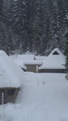 Wallpaper Mural Amidst tall, snow-laden trees, wooden cabins sit quietly in a white blanket of snow, reflecting a peaceful winter setting. vertical video Torontodigital.ca