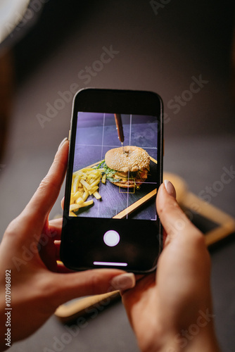 Capturing a gourmet burger and fries with a smartphone, a food photography moment photo