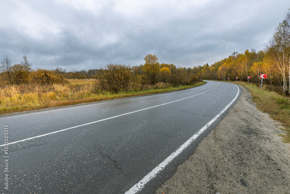 A road with a white line down the middle and a red sign on the side A road with a white line down the middle and a red sign on the side