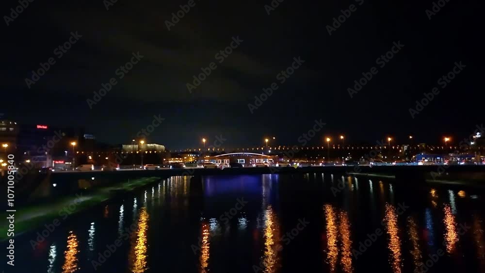 Night city. View of bridge over Vistula River in Krakow, Poland. lights of lanterns are reflected in water. Busy traffic on bridge in evening. Rush hour Night city. View of bridge over Vistula River in Krakow, Poland. lights of lanterns are reflected in water. Busy traffic on bridge in evening. Rush hour