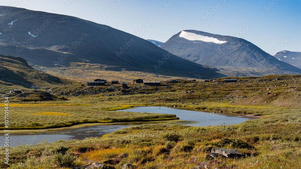 Beautiful view to the remote harsh nordic wilderness with tall mountains covered with snow, river and grassy highland meadows evokes retreat into the wild nordic landscape of autumn Lapland in Sweden. Beautiful view to the remote harsh nordic wilderness with tall mountains covered with snow, river and grassy highland meadows evokes retreat into the wild nordic landscape of autumn Lapland in Sweden.