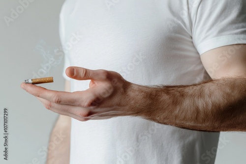 With a cigarette in his mouth against a light background, a man stands on the street