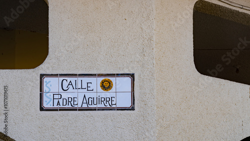 Ceramic street sign “Calle Padre Aguirre” on a textured wall in Cuenca, Ecuador. Traditional Spanish-style signage.