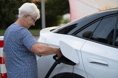 Senior Woman Connecting Electric Car to Charging Station