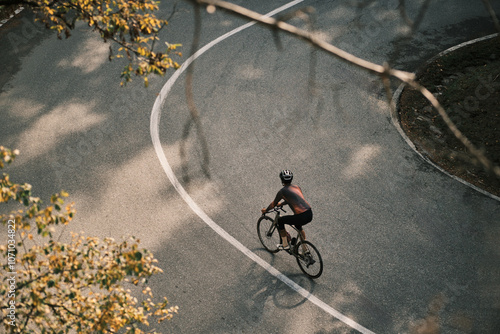 Cyclist on a scenic road curve. Aerial view of a person cycling through a vibrant landscape. Perfect for travel, sport, or lifestyle projects. Romania. Carpathian Mountains. Transylvania
