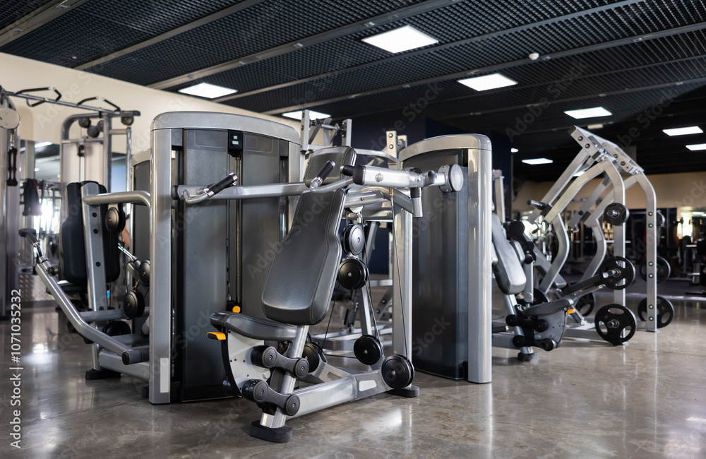 Fototapeta premium Interior of modern gym with weight training machines for beginners and professional athletes. Beneficial and safe equipment for muscle strengthening and bodybuilding