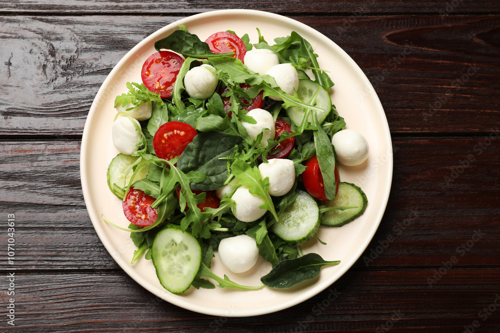 Tasty salad with arugula, spinach, mozzarella cheese and vegetables on wooden table, top view Tasty salad with arugula, spinach, mozzarella cheese and vegetables on wooden table, top view