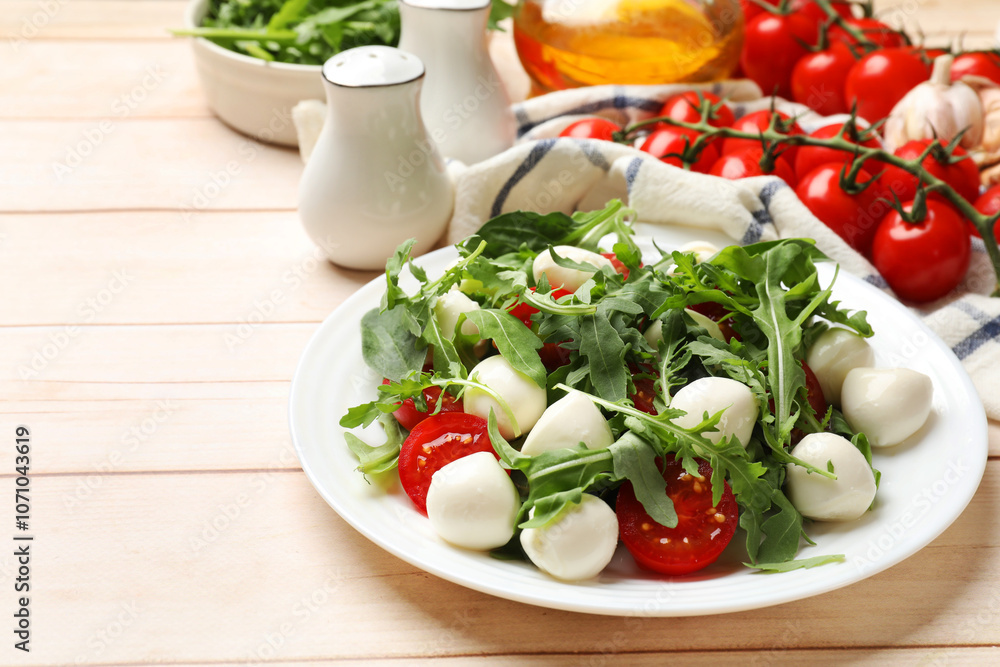 Tasty salad with arugula, spinach, mozzarella cheese and tomatoes on wooden table, closeup Tasty salad with arugula, spinach, mozzarella cheese and tomatoes on wooden table, closeup