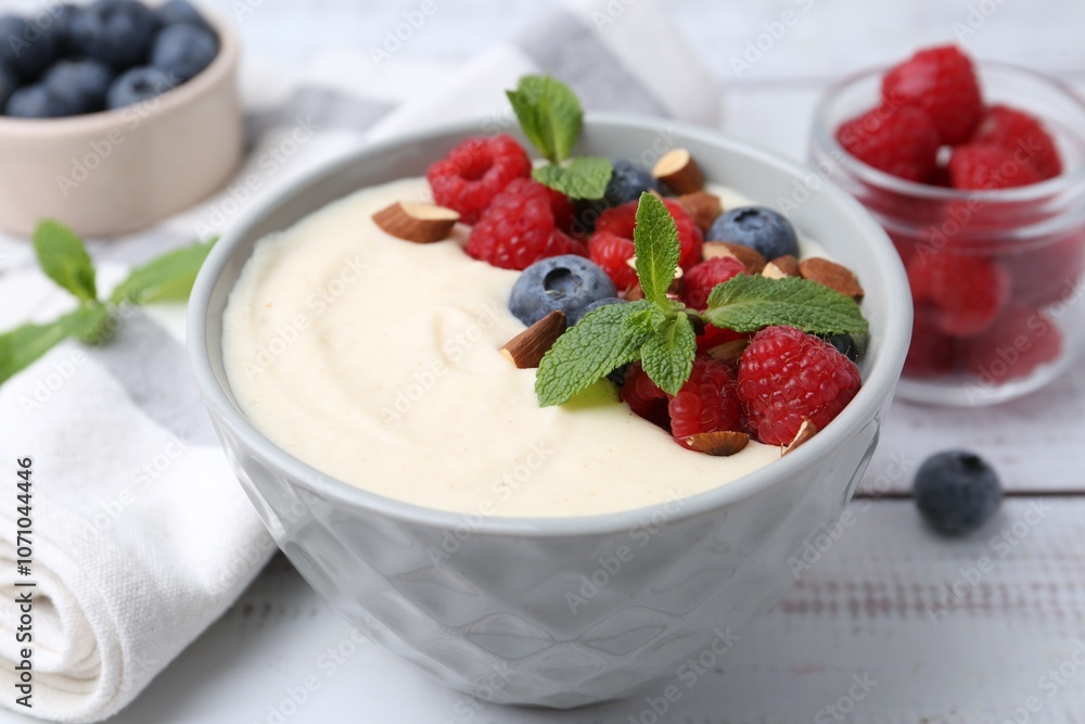 Tasty cooked semolina porridge with almonds, berries and mint on white wooden table, closeup Tasty cooked semolina porridge with almonds, berries and mint on white wooden table, closeup