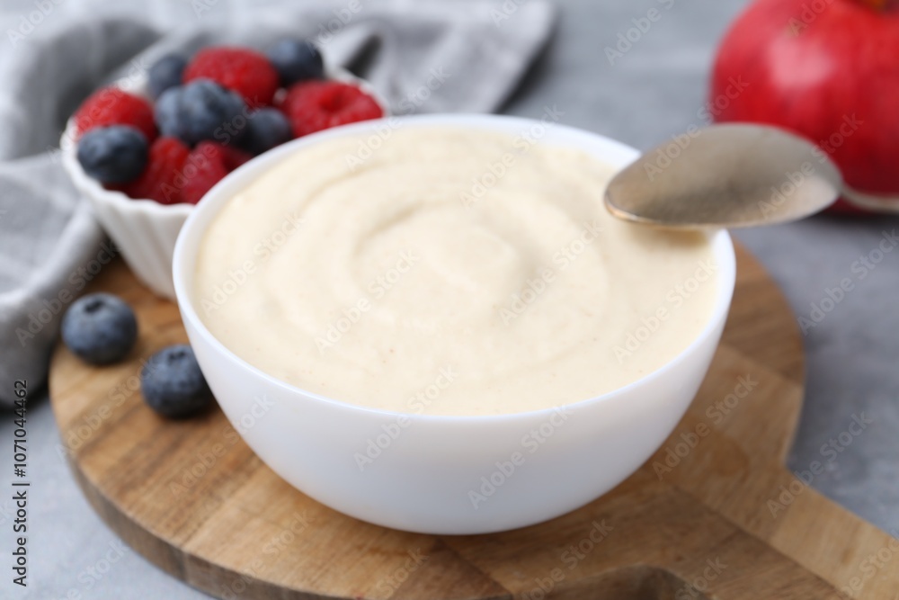 Tasty cooked semolina porridge in bowl and berries on grey table, closeup Tasty cooked semolina porridge in bowl and berries on grey table, closeup