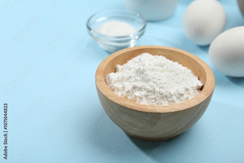 Baking powder in bowl, eggs and salt on light blue background, closeup. Space for text Baking powder in bowl, eggs and salt on light blue background, closeup. Space for text