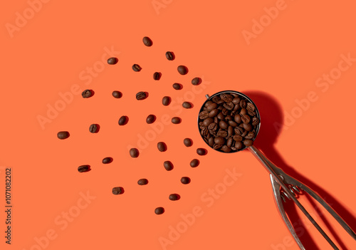 Coffee beans in an ice cream scoop on a orange background photo